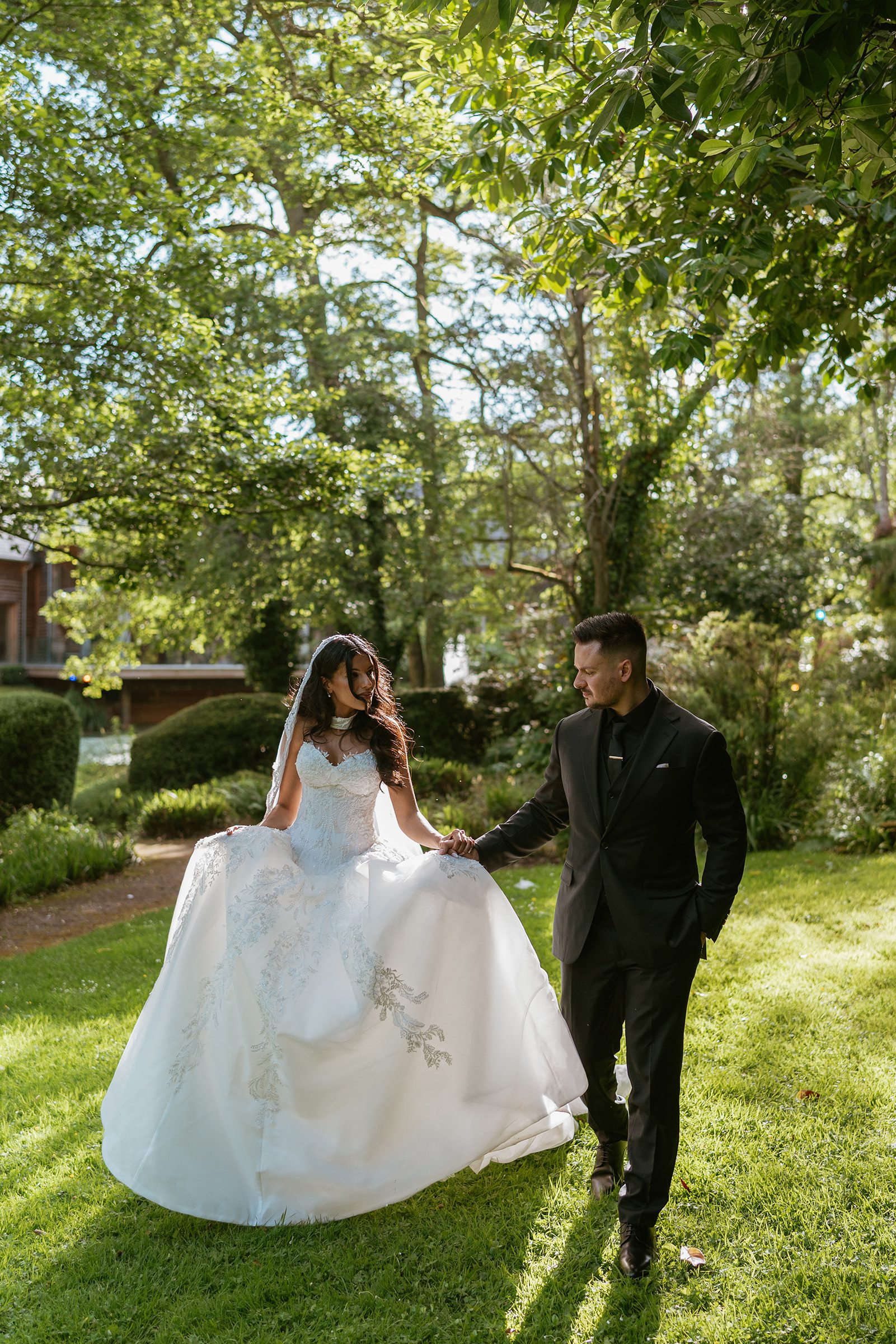 Nisha and Antoni walking hand in hand across the lawn at The Mill Barns, Shropshire